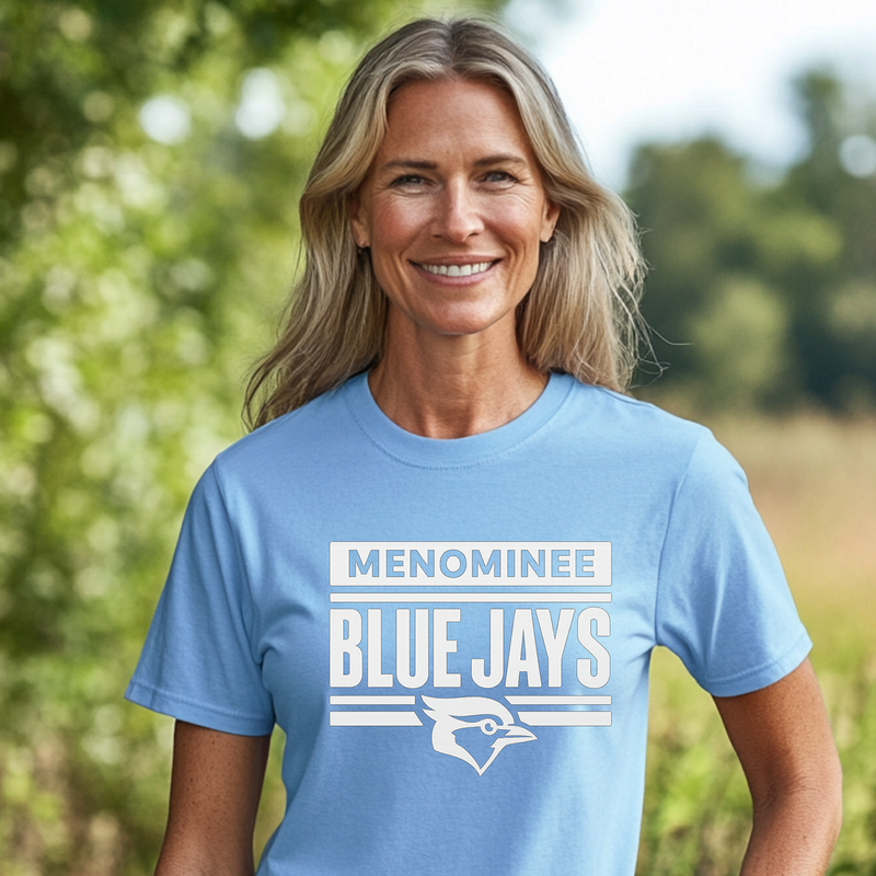 Woman wearing a blue t-shirt with 'Menominee Blue Jays' text and logo outdoors.